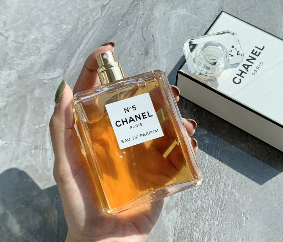 Hand holding a Chanel No. 5 Eau de Parfum bottle with the packaging in the background.