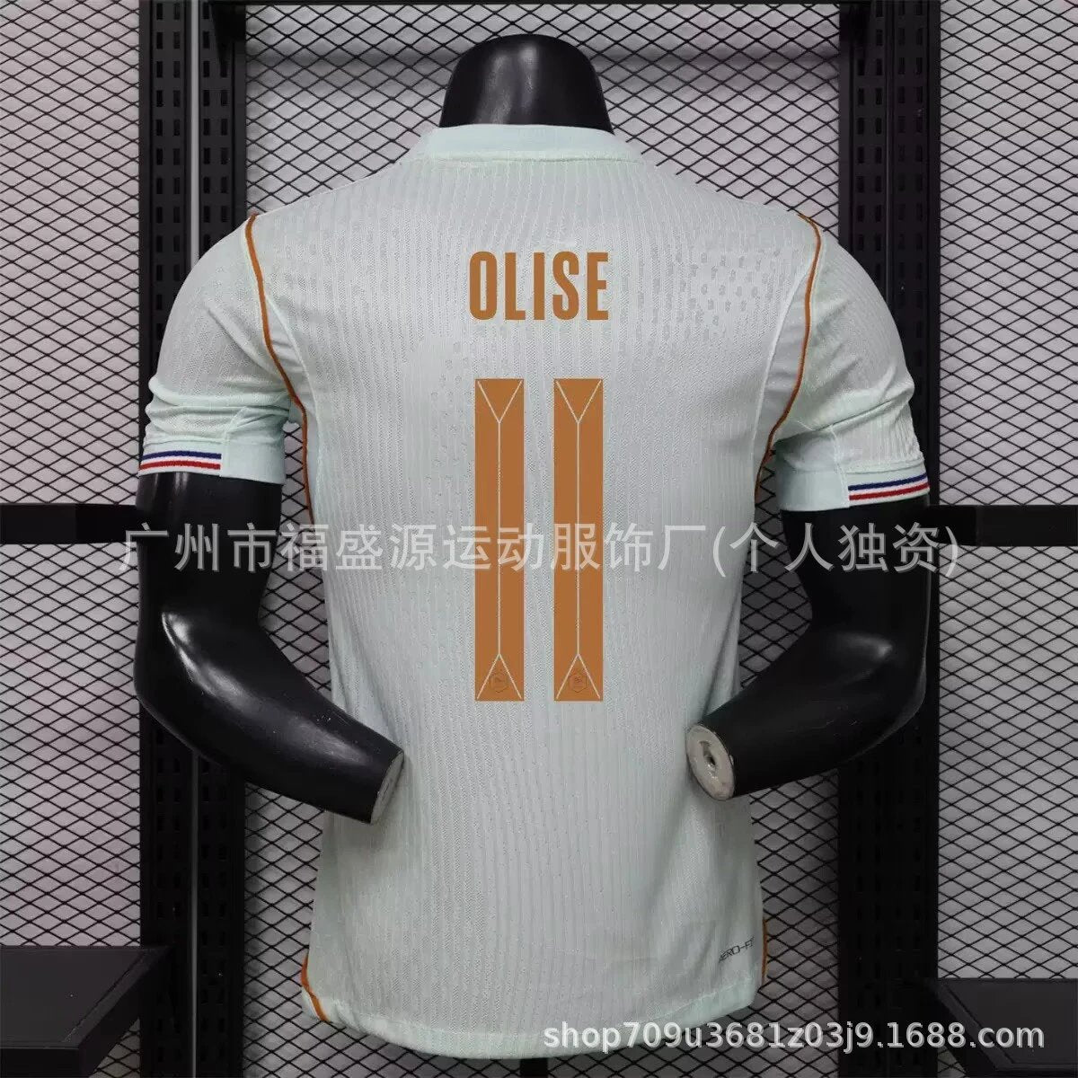 Light blue sports jersey with 'OLISE' branding on a mannequin against a black grid background.